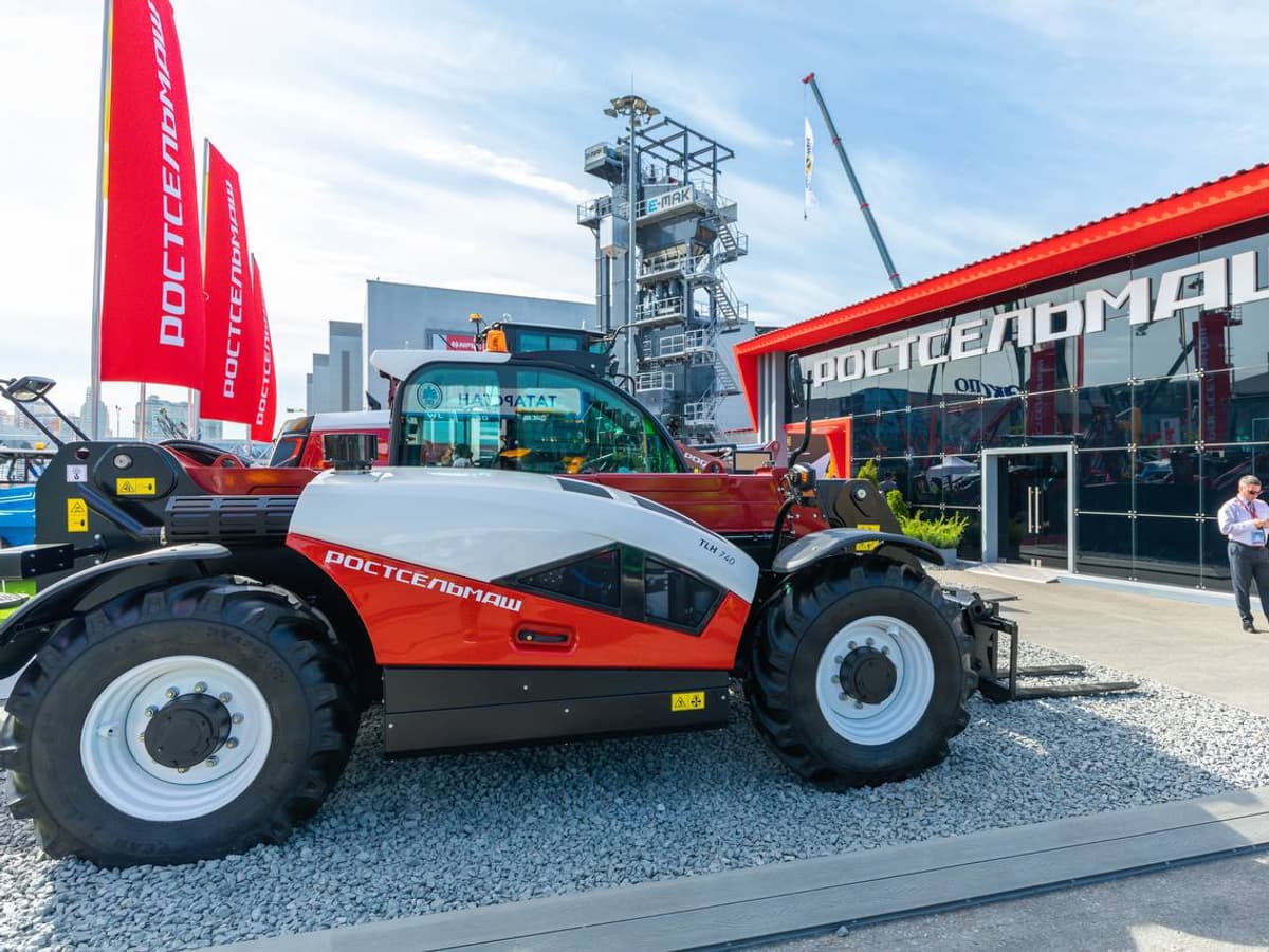 Телескопический погрузчик Ростсельмаш TLH 740 в работе на строительной площадке, мощная стрела поднята, демонстрирует грузоподъёмность и высоту подъёма