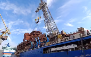 Trabajadores con la ayuda de la grúa flotante "Demag" cargaron un bloque de 200 toneladas en el rompehielos "Chukotka"