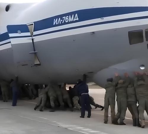 Military personnel push an Il-76MD